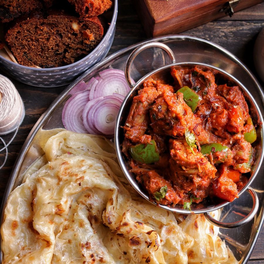 A bowl of curry served with flatbread and sliced onion (illustrative stock photo)